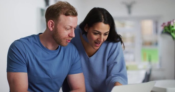 4K Happy smiling couple browsing the internet together at home. Slow motion.
