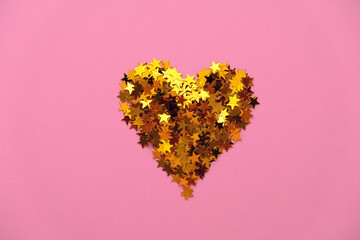 Gold sequins in the shape of a heart on a pink background