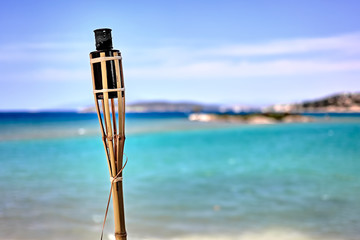 Dim bamboo torch at the beach against sea background. Close up with copy space
