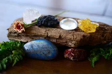 Variety of healing crystals on wooden table. Rose Quartz, Tektite, Labradorite, Brecciated Jasper, Amber, and Clear Quartz. Crystals of all shapes and sizes, natural lighting. Shiny witchy crystals.