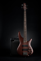 Maroon bass guitar and black amplifier on black background