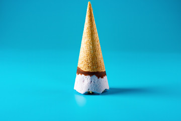 peanut ice cream cone upside down stands on blue background