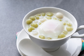 Pandan Thai glutinous rice balls (Bua Loi) in white bowl on table,Boiled egg.