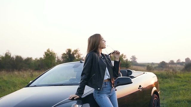 Attractive young woman standing near cabriolet.