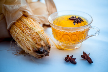 Beneficial detoxifying corn tea in a glass cup isolated on white along with some Star anise...