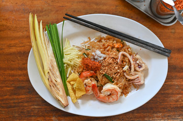Pad thai , Thai style noodle with shrimps on white dish and wooden table