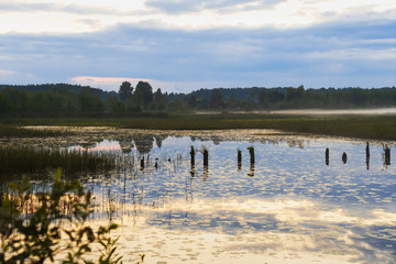 House on the shore of a marshy lake in the evening at sunset light.