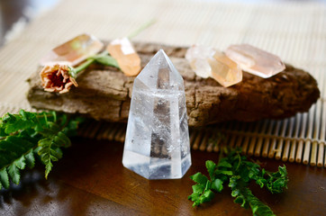 Beautiful Clear Quartz tower, and fresh pink rose flowers. Bright Quartz crystal, healing crystal being held in hand. Woman holding quartz tower, crisp colors in natural lighting. Vibrant meditation.