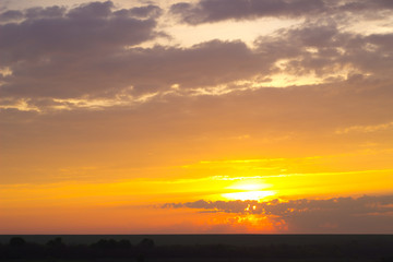 Naklejka na ściany i meble beautiful dawn. yellow sun rising above the horizon in the clouds