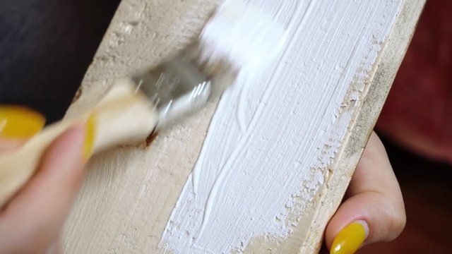 painting a wooden board with a white paint brush close-up