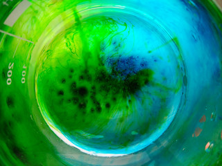 The blue and green crystals of dye fells to the bottom of the beaker and slowly dyed the aqueous...