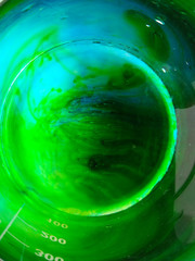 The process of dissolving food dyes in water in a beaker, blue and green tetrazines.