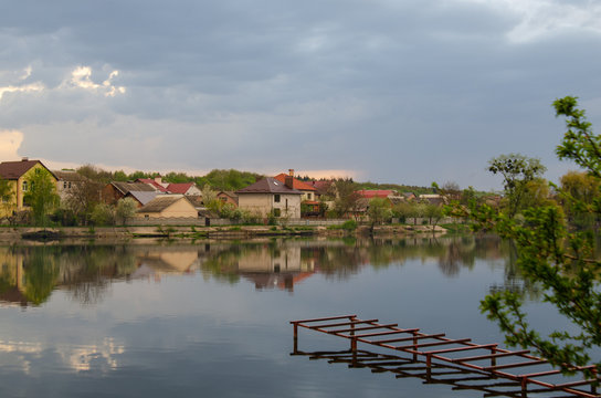 Lake in a village with a reflection of the sky before the rain