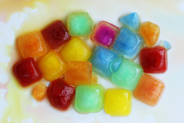 A large number of colored ice cubes are melting.