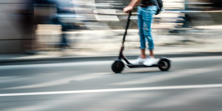 Elektroroller f&auml;hrt auf einer Stra&szlig;e durch die Stadt
