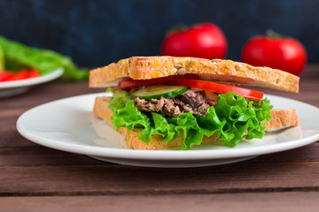 sandwich with tuna cereal bread  lettuce tomato cucumber on white plate soft focus