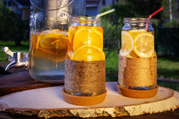 Lemon and orange lemonades on country background