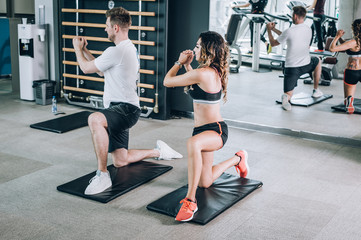 Fototapeta na wymiar Attractive fitness woman with coach doing hard exercise in gym