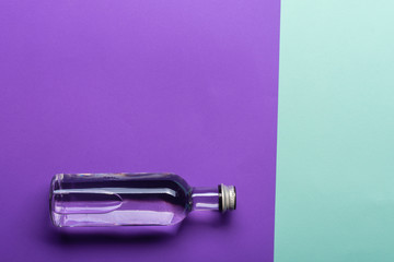 bottle with water on bright purple and azure background 