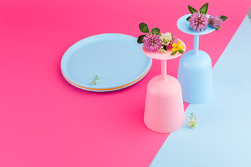 Plastic colored glasses for lunch in the open air. Crockery bright colors on a pink background. Copy space.