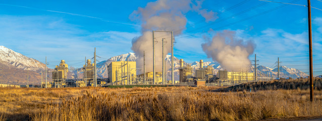 Power Plant with thick smoke rising against the blue sky viewed on a sunny day