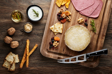 Flat lay view of Turkish skinbag cheese (divle obruk) on a wooden cutting board decorated with props