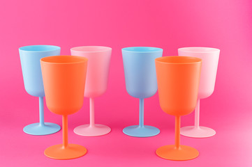 Colored plastic picnic utensils in bright colors. Glasses of blue and pink. Eco dishes.