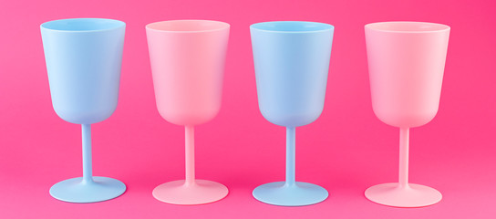 Colored plastic picnic utensils in bright colors. Glasses of blue and pink. Eco dishes. Banner.
