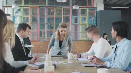 Business woman team leader begins meet up with employees, sits down at the table and opens the laptop. Creative office interior. Coworking startup team. Office life