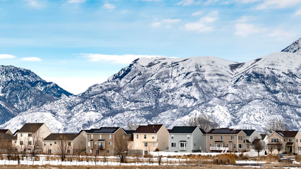 Clear Panorama Beautiful blue sky with puffy clouds over homes and mountain in winter