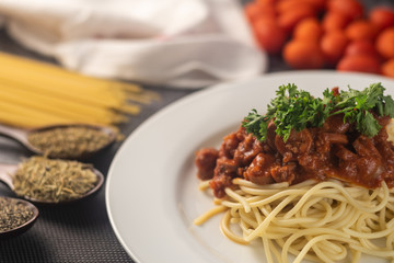 a plate of spaghetti served with the beef tomato sauce with ingredients on the mat. selective focus