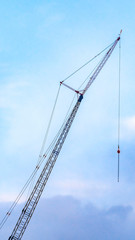 Clear Vertical A lifting crane viewed against a beautiful blue sky filled with cottony clouds