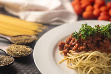 a plate of spaghetti served with the beef tomato sauce with ingredients on the mat. selective focus