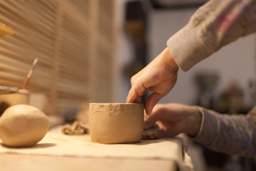 Female potter works with ceramic at his workshop. Young woman work inside 
