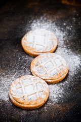 Fresh baked tarts with chocolate filling and sugar powder on black  background.