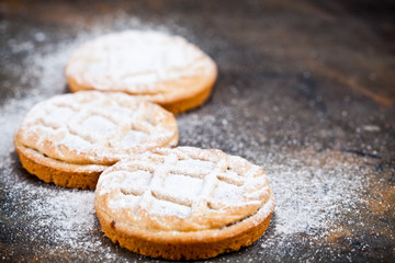 Fresh baked tarts with chocolate filling and sugar powder on black  background.