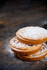 Fresh baked tarts with chocolate filling and sugar powder on black  background.