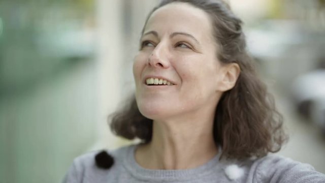 Beautiful smiling middle aged brunette talking to camera. Attractive mature woman looking at camera and blowing air kiss. Concept of storytelling
