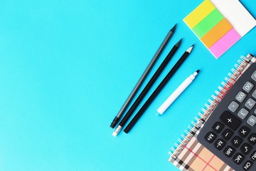Top view of blue office desk with pencils, calculator and notebook. Back to school concept.