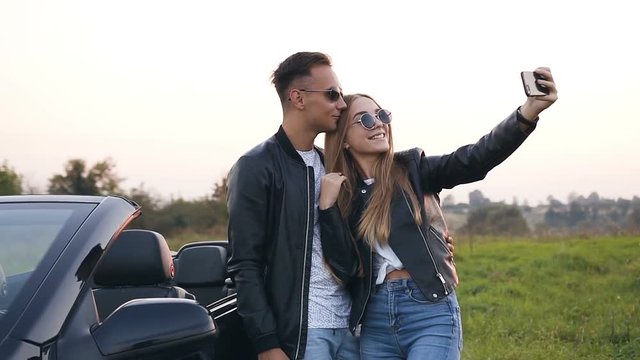 Handsome couple in love taking selfie standing near the car. cabriolet.