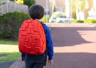 Rear view portrait of Cheerful school boy carrying backpack walking to school, Pupil of primary going to school, Young student beginning of class after school holiday,Back to school concept