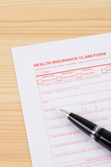 Health insurance claim form with pen on wooden desk