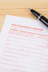 Health insurance claim form with pen on wooden desk