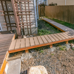 Square Wooden walkway inside the yard of a home viewed on a sunny day