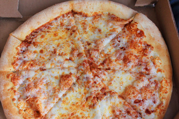Cheese margarita pizza with melted mozzarella and fresh tomato sause in delivery box top view 