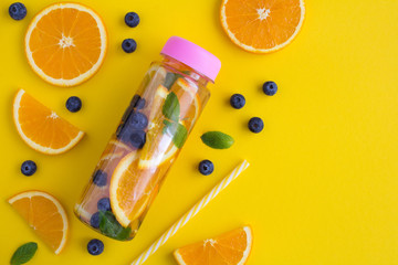 Infused or detox water with orange  and blueberry  in the bottle  on the yellow background.Top...