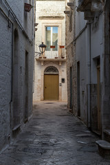 Una calle estrecha encalada de blanco en un pueblo medieval de la región de Puglia en Italia