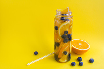 Infused or detox water with orange  and blueberry  in the bottle  on the yellow background.Copy...
