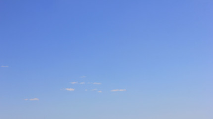 Blue sky background with small cloud texture. Empty cloudscape with peaceful sunny day sky surface 