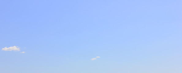 Empty pale blue sky background with small clouds 